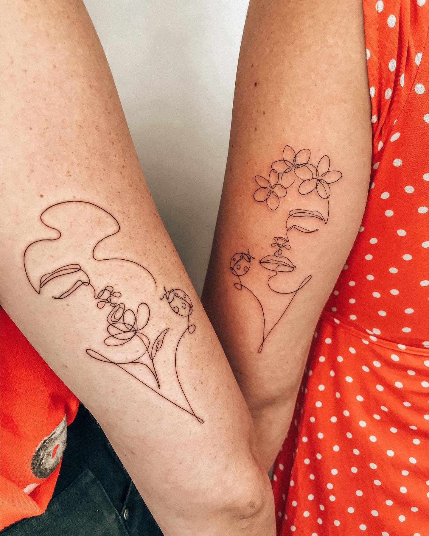 Matching minimalist tattoos of a woman's face and a flower in continuous line art, symbolizing femininity and connection